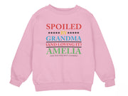 a young girl wearing a pink sweatshirt with the words spoiled by grandma and loving by